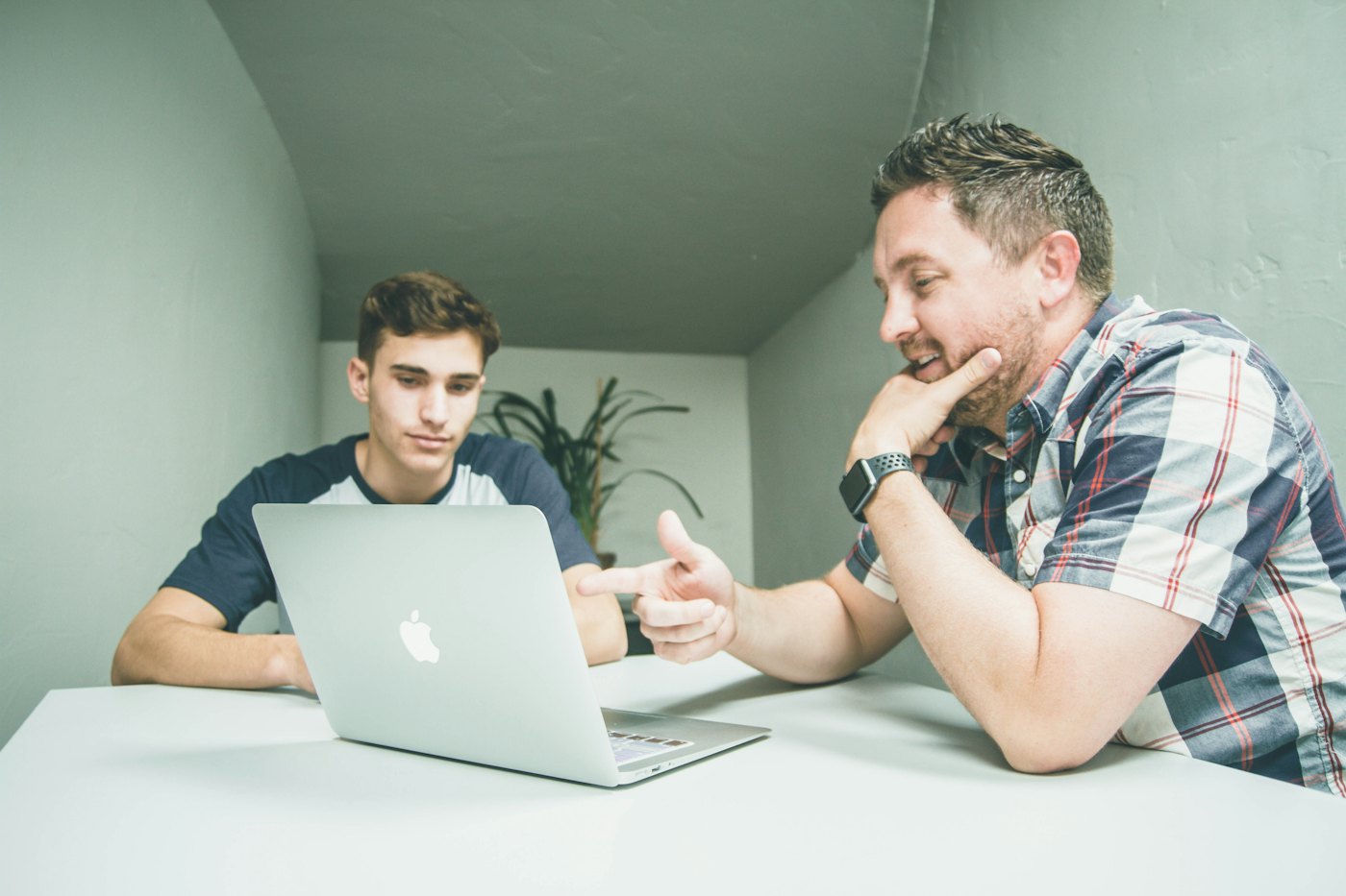 A mentor talking a teenager through something on a laptop